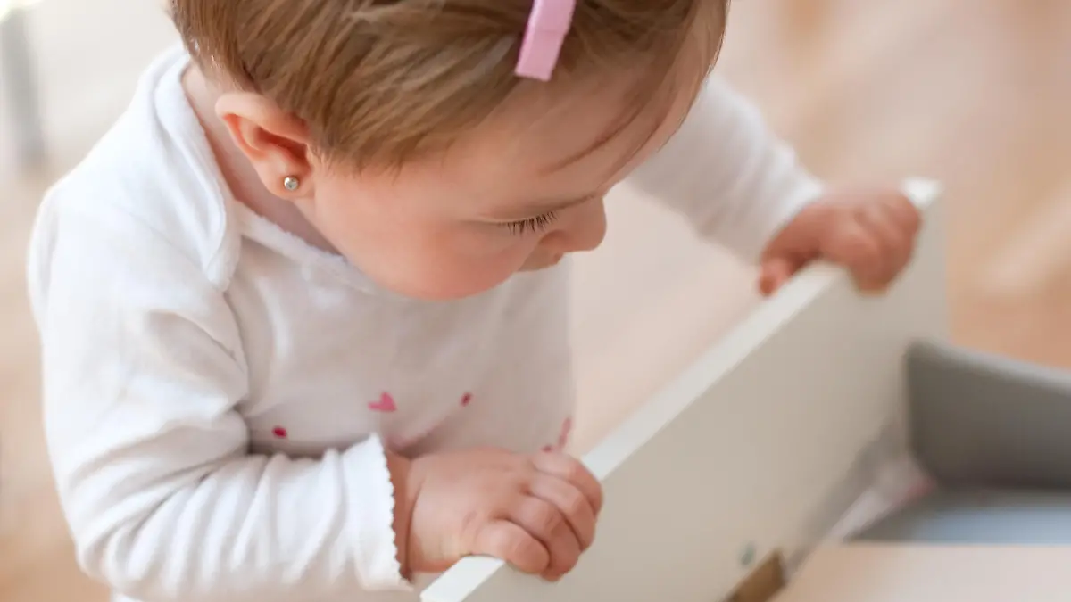 Baby girl looking inside a drawer with curiosity. Risks at home with little children. Focus in the eye.