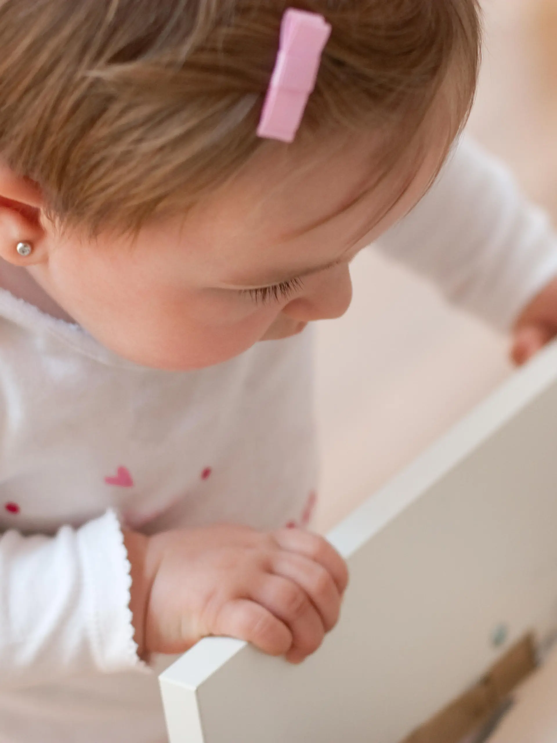Baby girl looking inside a drawer with curiosity. Risks at home with little children. Focus in the eye.