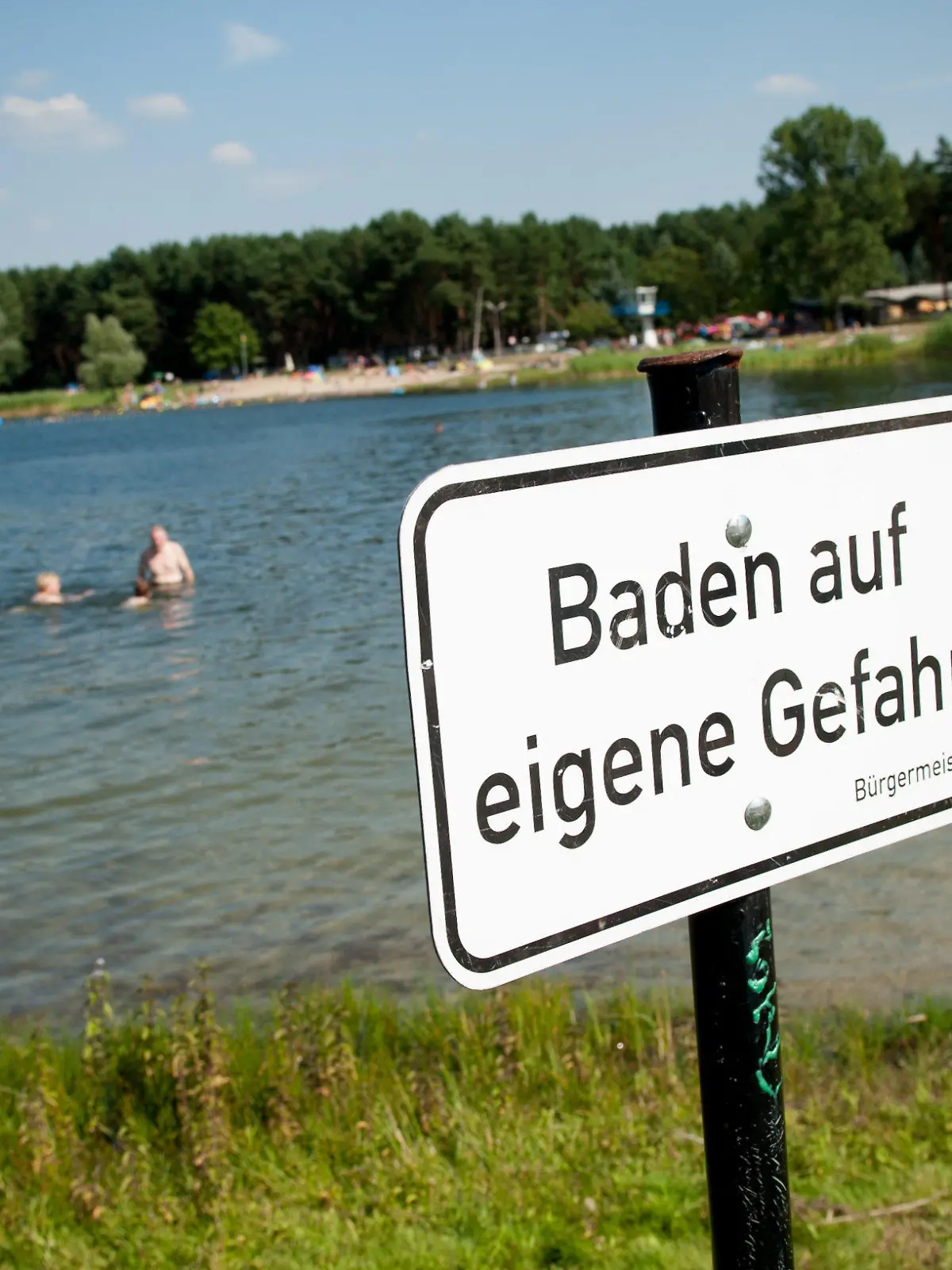 Ein Gefahrenschild mit der Aufschrift « Baden auf eigene Gefahr » steht am 18.07.2014 am Bernsteinsee in Velten (Brandenburg). Foto: Oliver Mehlis/dpa +++(c) dpa - Bildfunk+++