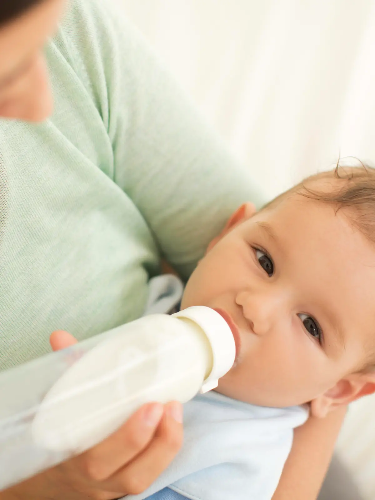 Mother feeding her baby boy with milk from a bottle.