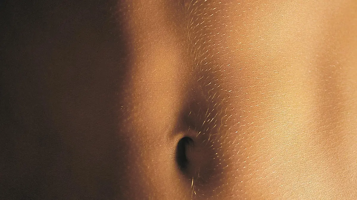 Der nackte Bauch eines Menschen mit feinen Härchen.