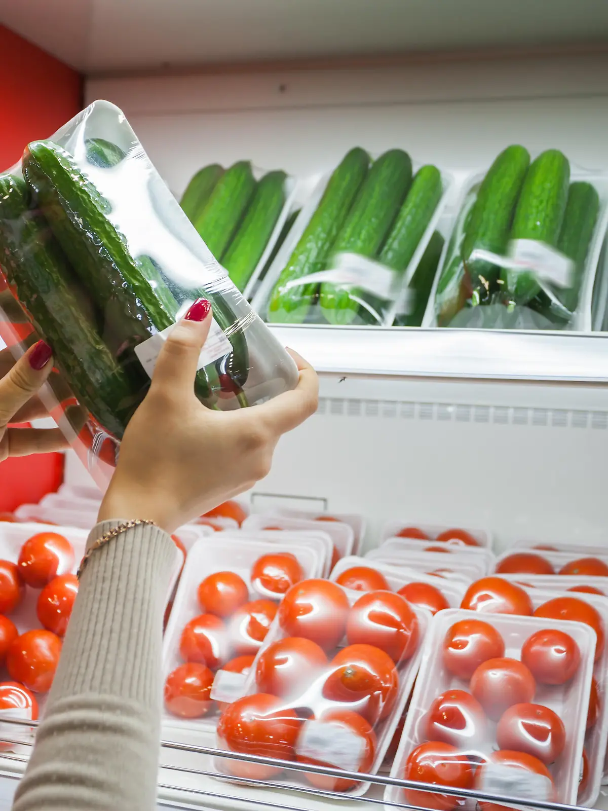 Image of packaged cucumber with woman hand in the supermarket