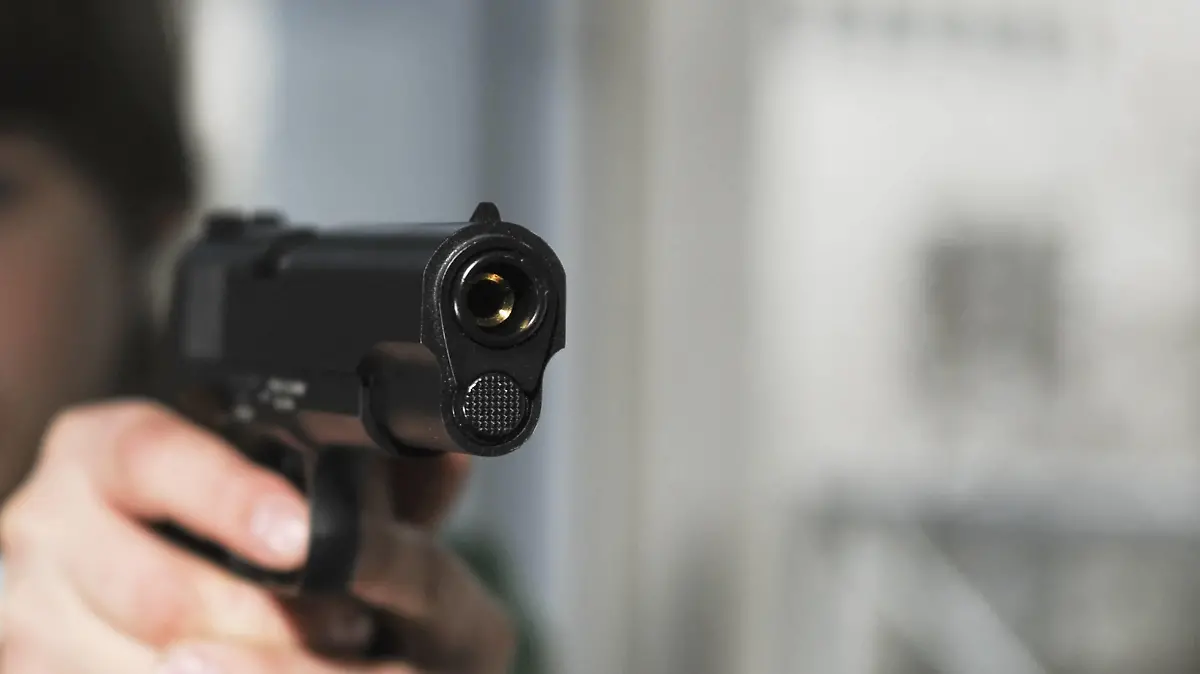 Boy aims Colt 1911 pistol |