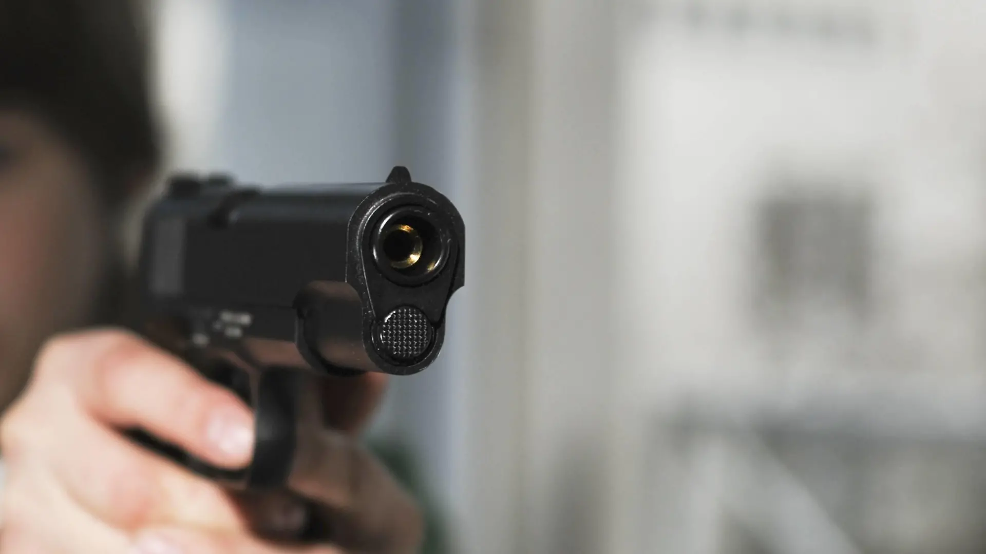 Boy aims Colt 1911 pistol |