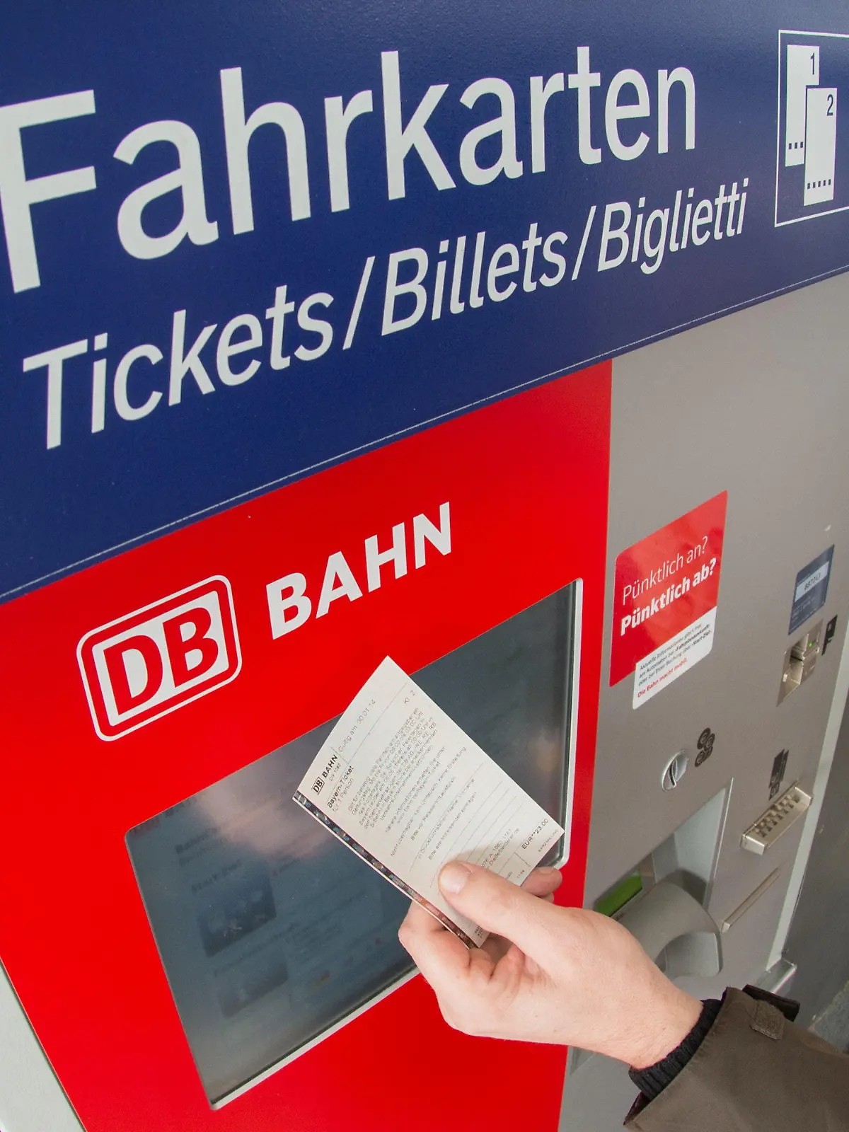 ARCHIV - 30.01.2014, Bayern, Straubing: ILLUSTRATION - Ein Fahrgast hält ein Ticket vor einen Fahrkartenautomaten der Deutschen Bahn. Die Deutsche Bahn schafft das Schöne-Wochenende-Ticket ab. Foto: Armin Weigel/dpa +++ dpa-Bildfunk +++