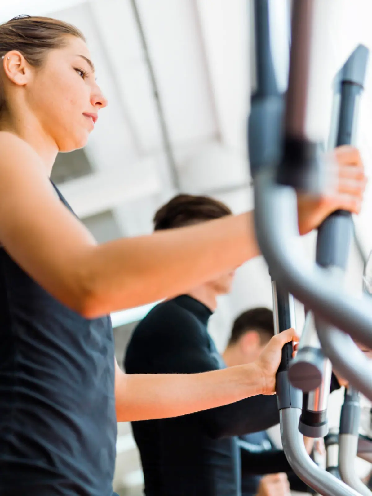 Beautiful fit young woman working out on a stepper together with her friends
