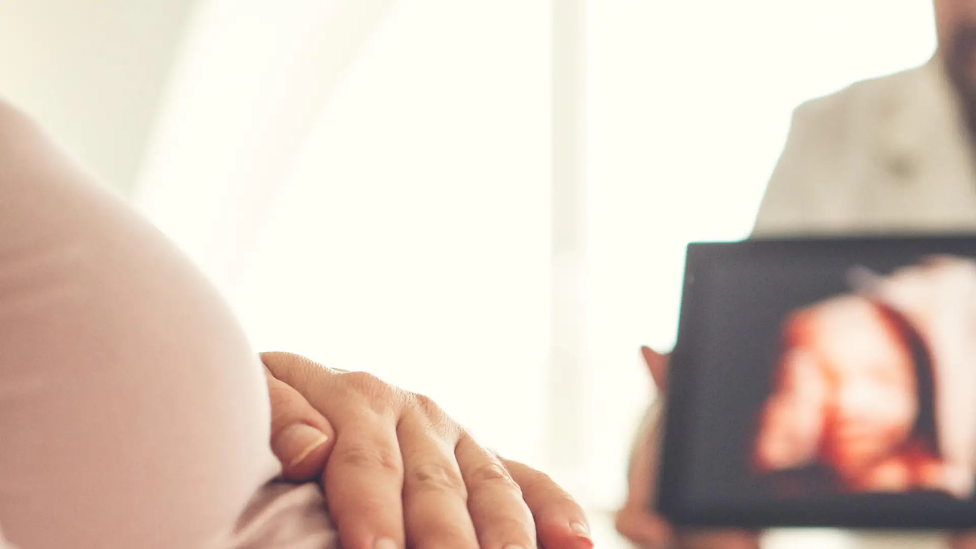 Pregnant woman looking at ultrasound image of her baby at doctor's office.