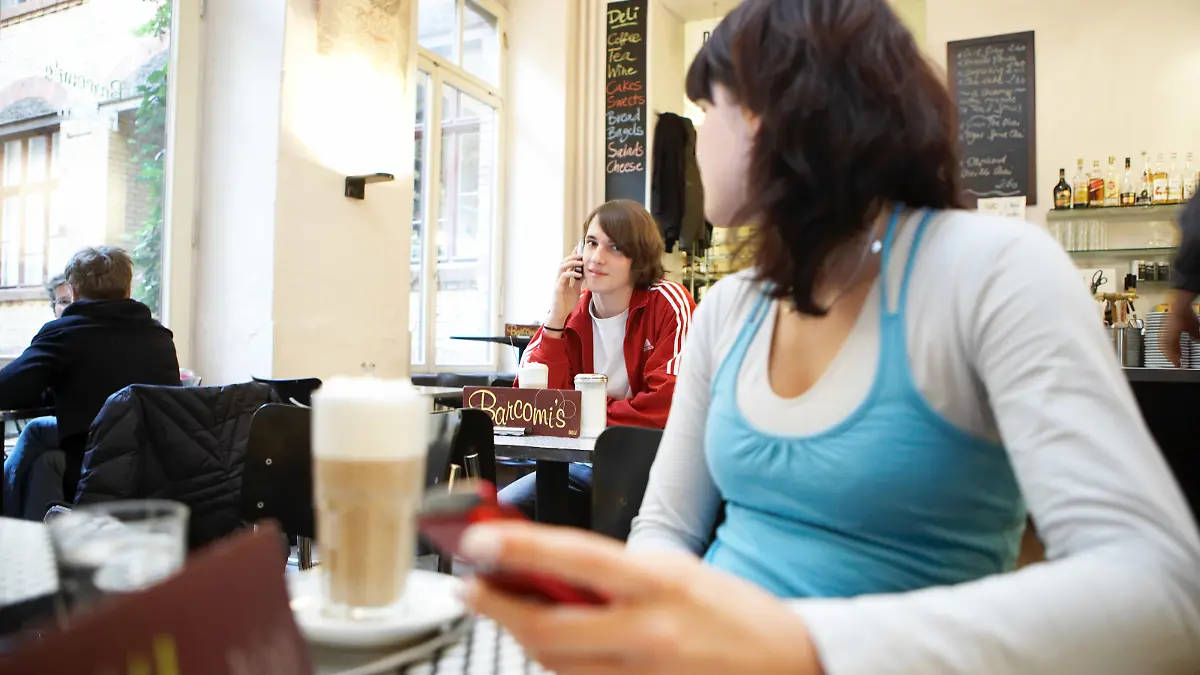 Eine junge Frau und ein junger Mann sitzen in einem Cafe in Berlin-Mitte und telefonieren mit ihren Handys und schauen sich an, aufgenommen am 02.12.2006 (Symbolbild zum Thema Jugend, Flirten, Verlieben, Bekanntschaft, Kennenlernen, Handy) Foto: Jörg Lange - Model release vorhanden - +++(c) dpa - Report+++