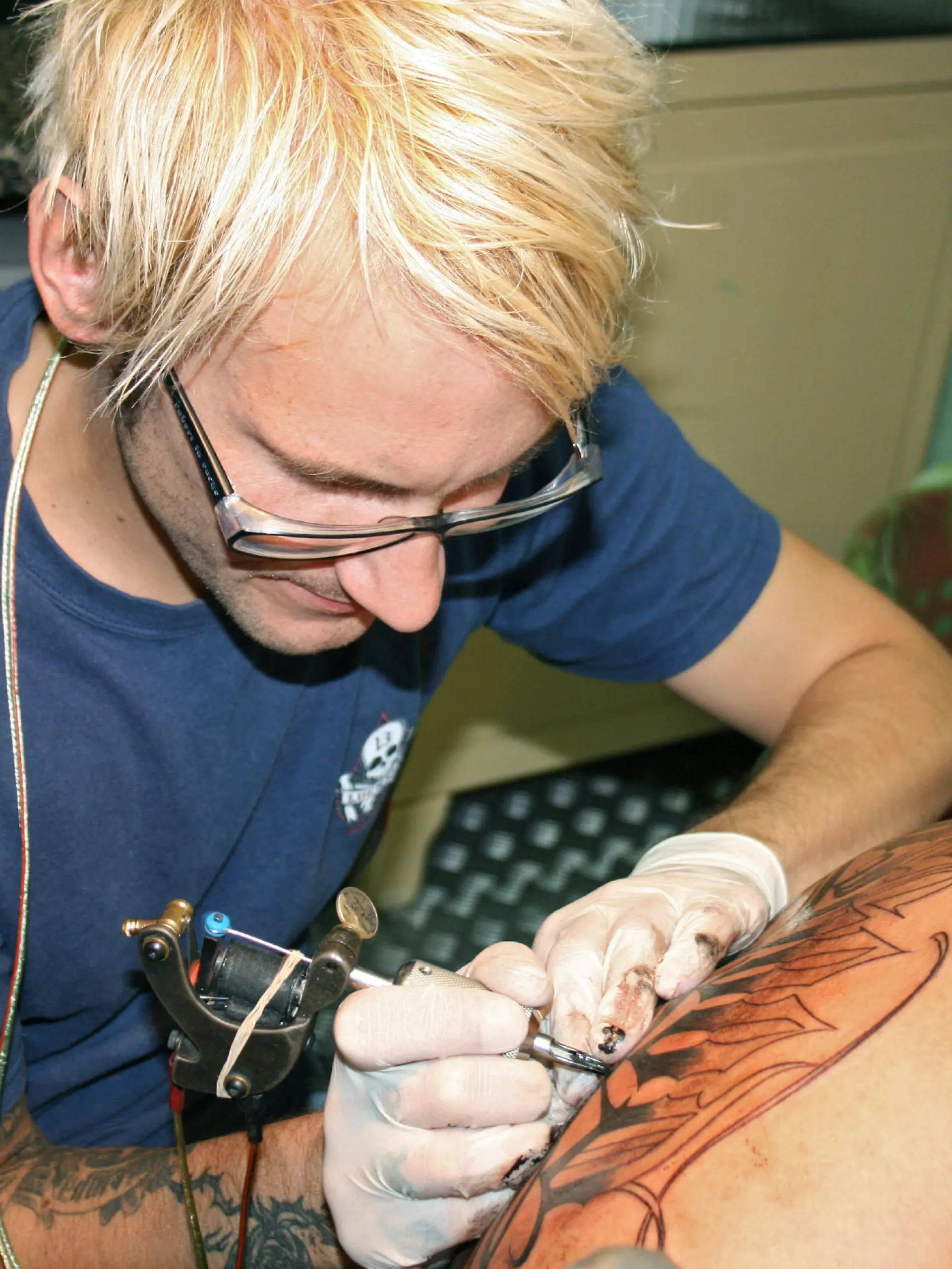 In einem Tattoo-Studio in Hamburg sticht ein Tätowierer einem Mann einen Schriftzug auf den Rücken (Aufnahme aus dem Juli 2008). Volle Konzentration: Tätowierer müssen sehr genau arbeiten. Wenn sie Fehler machen, bleiben die für immer. Foto: Silke Fokken, dpa ACHTUNG: Nur für Bezieher des Dienstes dpa-Nachrichten für Kinder.  +++(c) dpa - Report+++