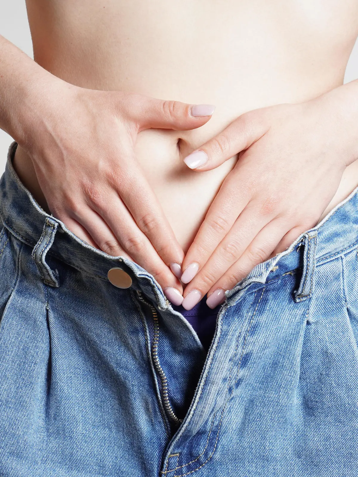 woman in jeans hands holding belly with abdominal or period pains || Modellfreigabe vorhanden