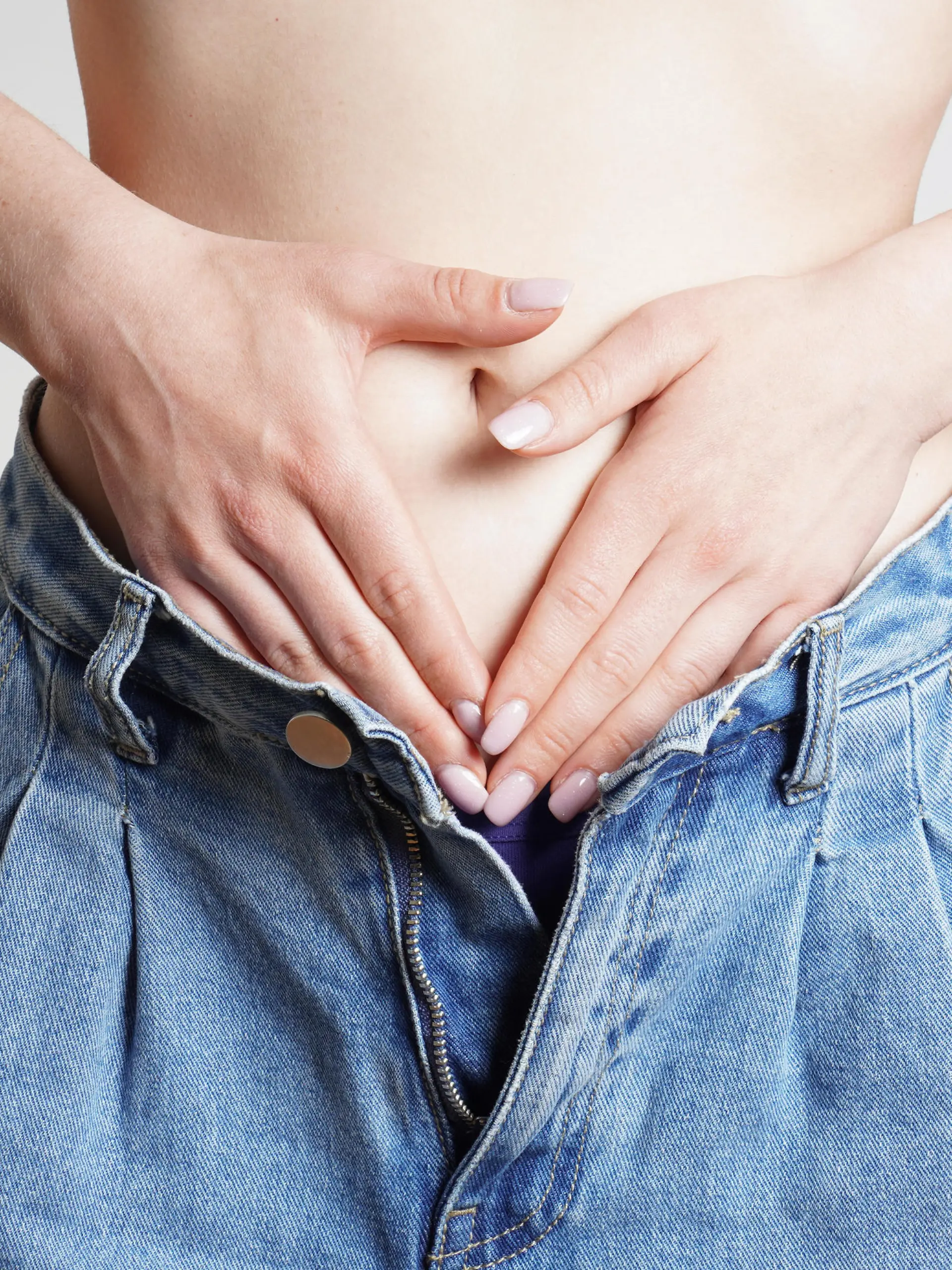 woman in jeans hands holding belly with abdominal or period pains || Modellfreigabe vorhanden