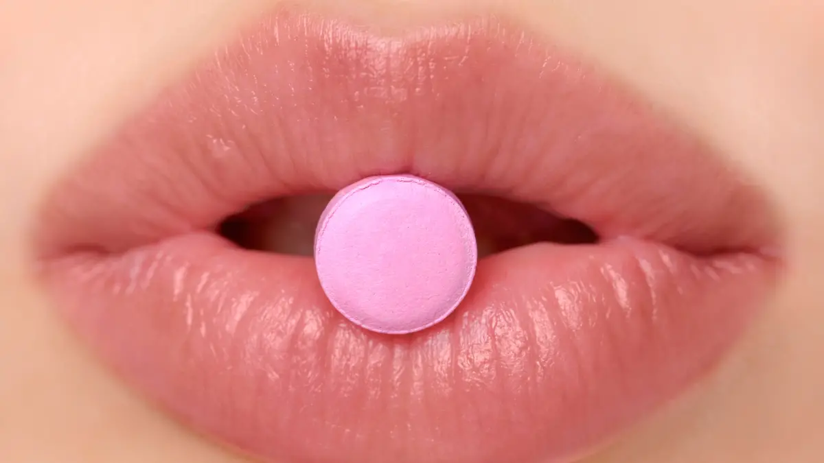 Close-up of pink pill in woman's mouth