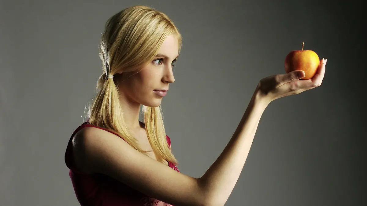 Eine junge, blonde Frau hält einen Apfel in der Hand, aufgenommen am 21.12.2005. Illustration zu den Themen Diät, Frühjahrskur, Vitamine, Obst, Ernährung, Eva und der Apfel, Versuchung, Verführung. Foto: TUOMAS MARTTILA / / MODEL RELEASED +++(c) dpa - Report+++