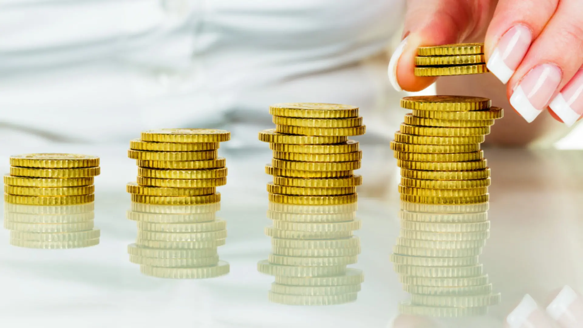 Eine Frau stapelt Münzen. Geld sparen für die Zukunft.