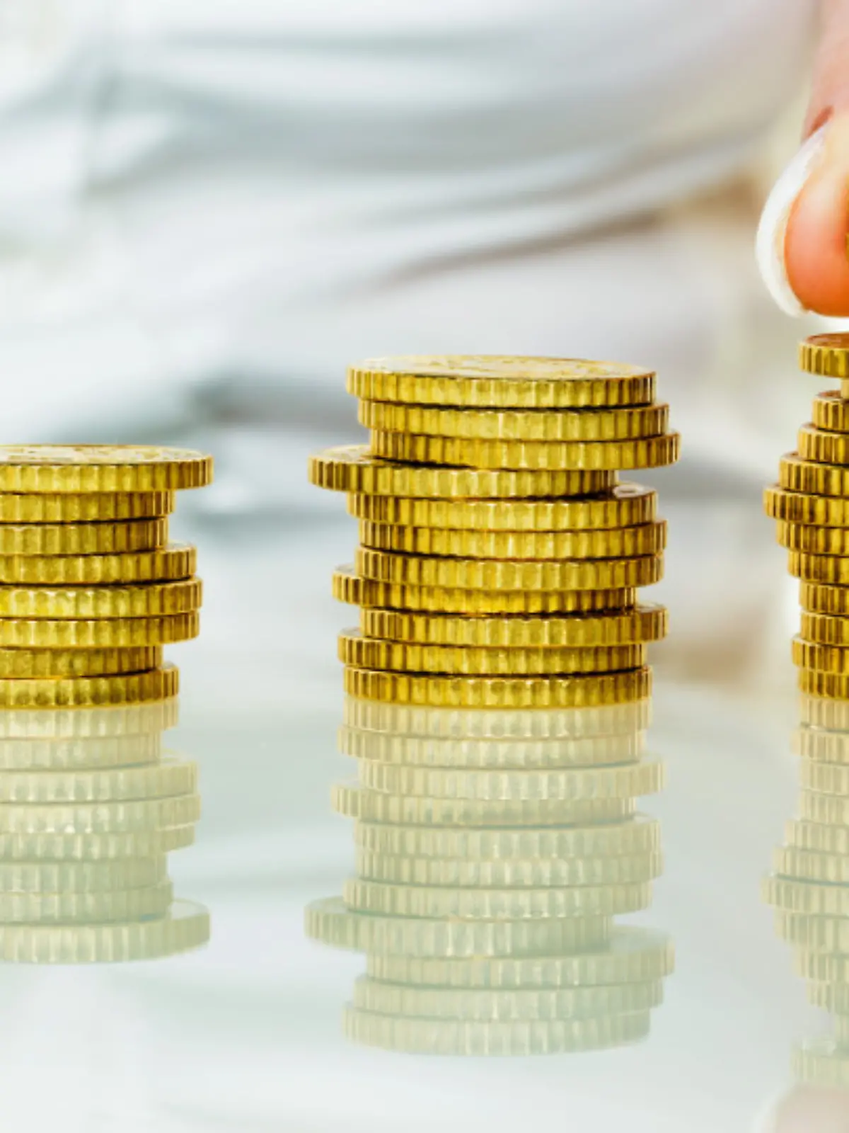 Eine Frau stapelt MÃ¼nzen. Geld sparen fÃ¼r die Zukunft.