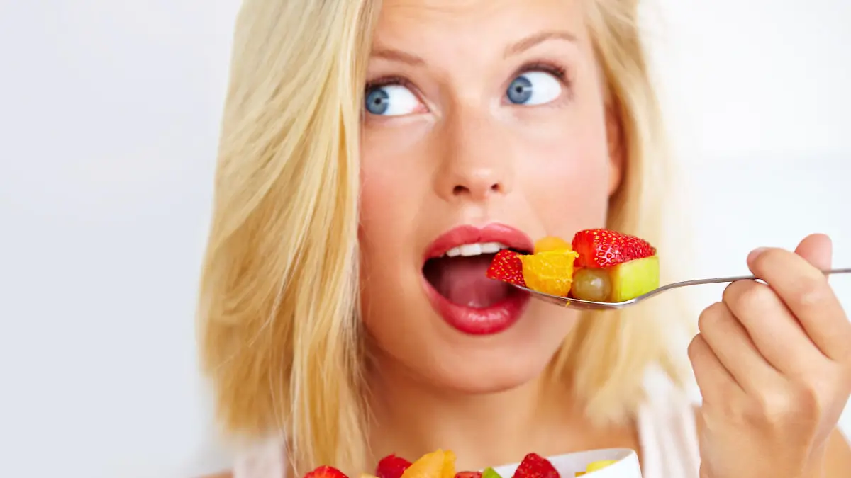 Beautiful young woman enjoying a salad with widened eyes while looking away