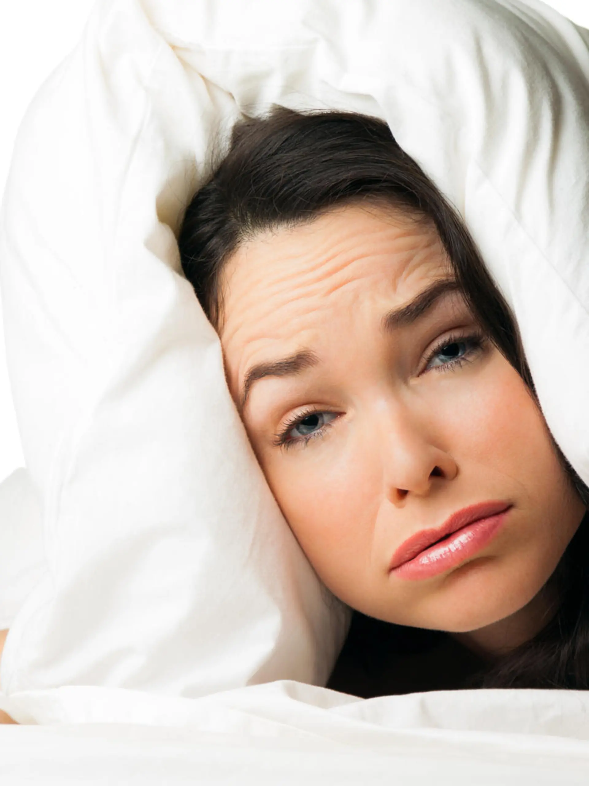 A tired sleepless woman with the pillow over her head . Isolated over white.