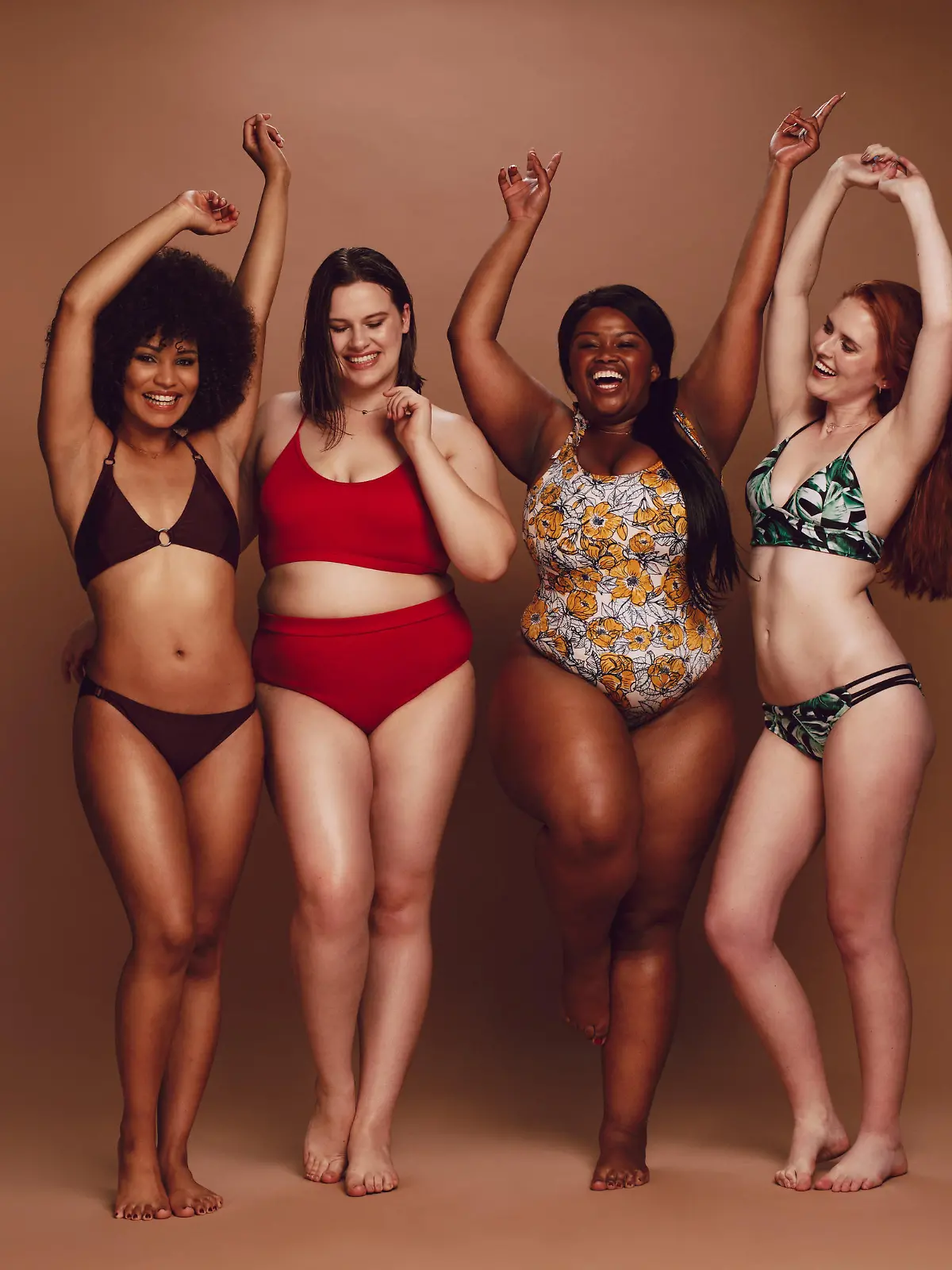 Frauen mit verschiedenen Körper-Typen haben Spaß bei einem Fotoshooting zusammen und präsentieren verschiedene Bademoden-Trends.
