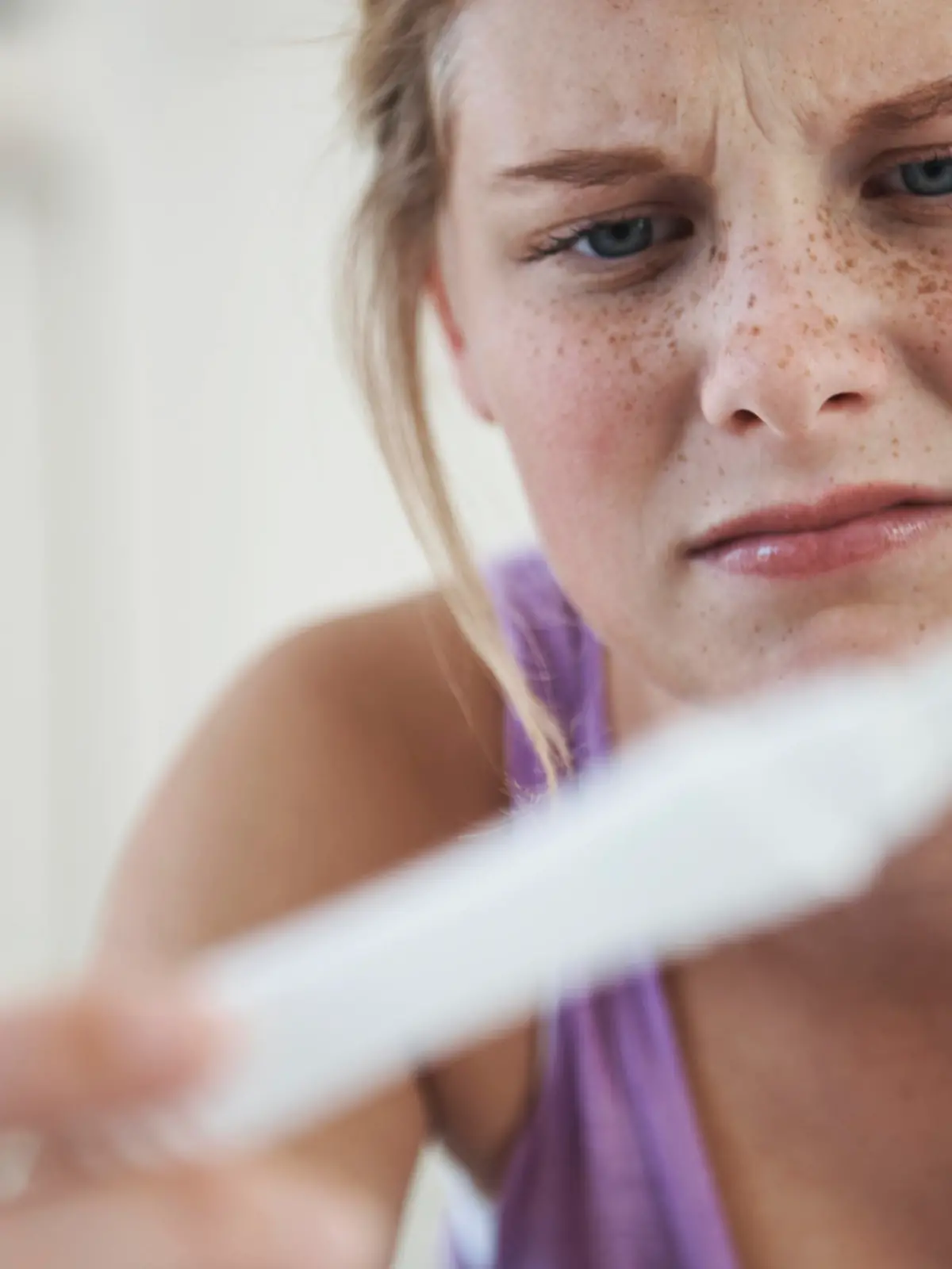 A teenage girl looking dismayed as she sees the result of a pregnancy text