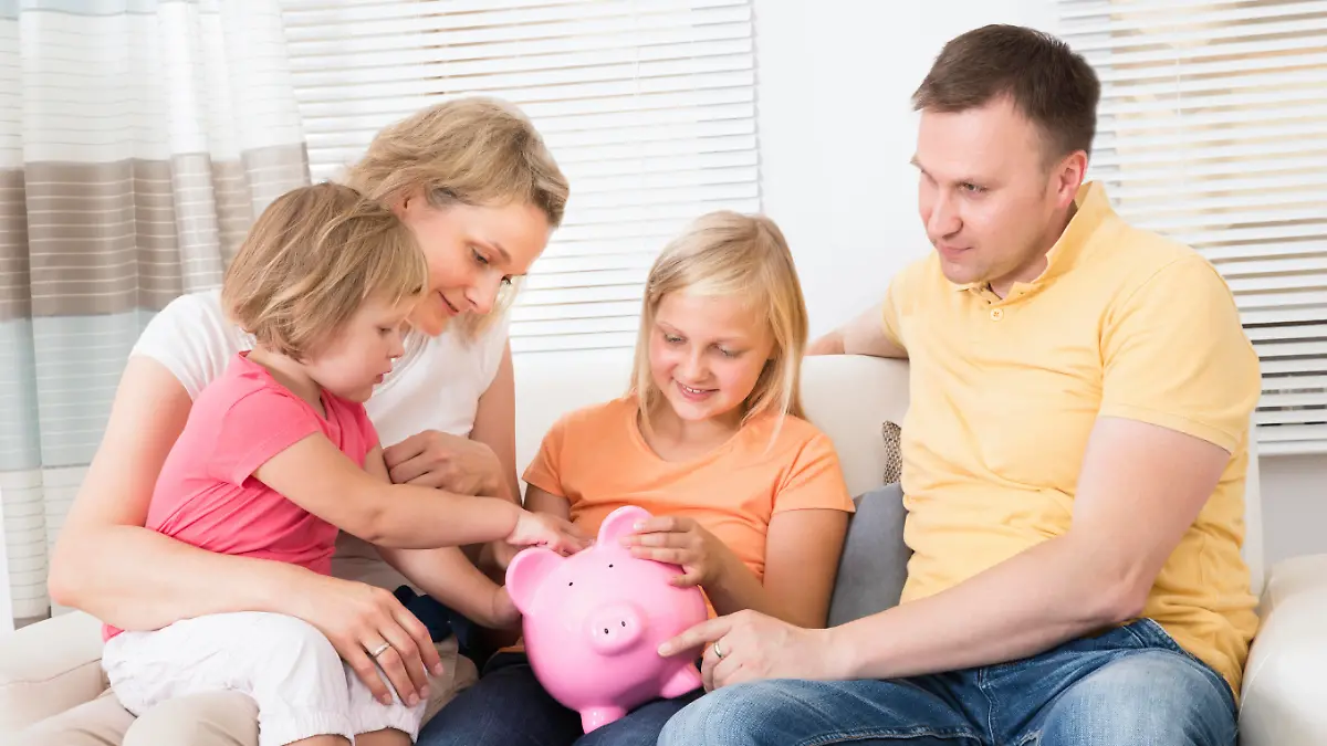 Family Saving Money In Piggybank At Home