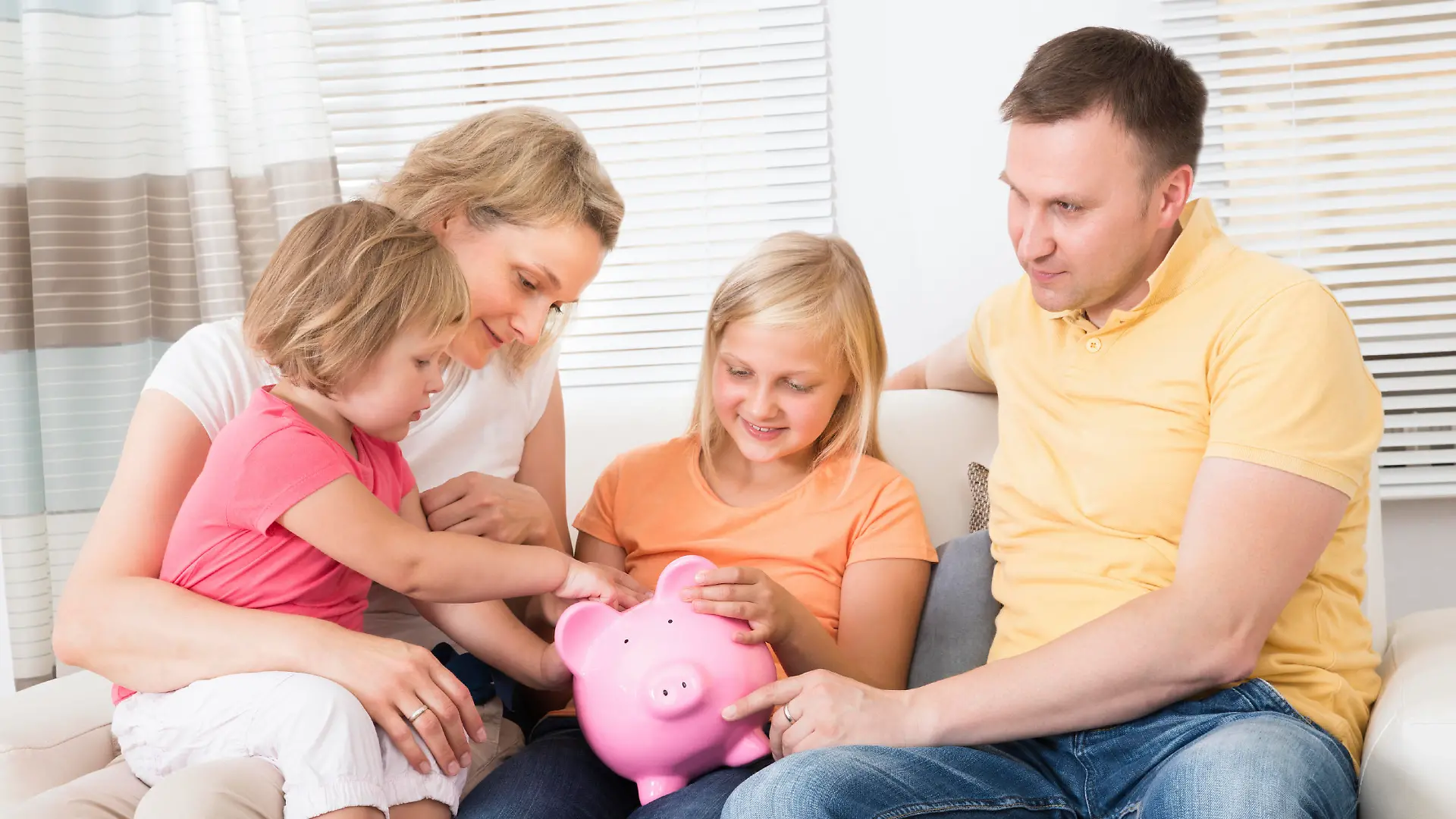 Family Saving Money In Piggybank At Home