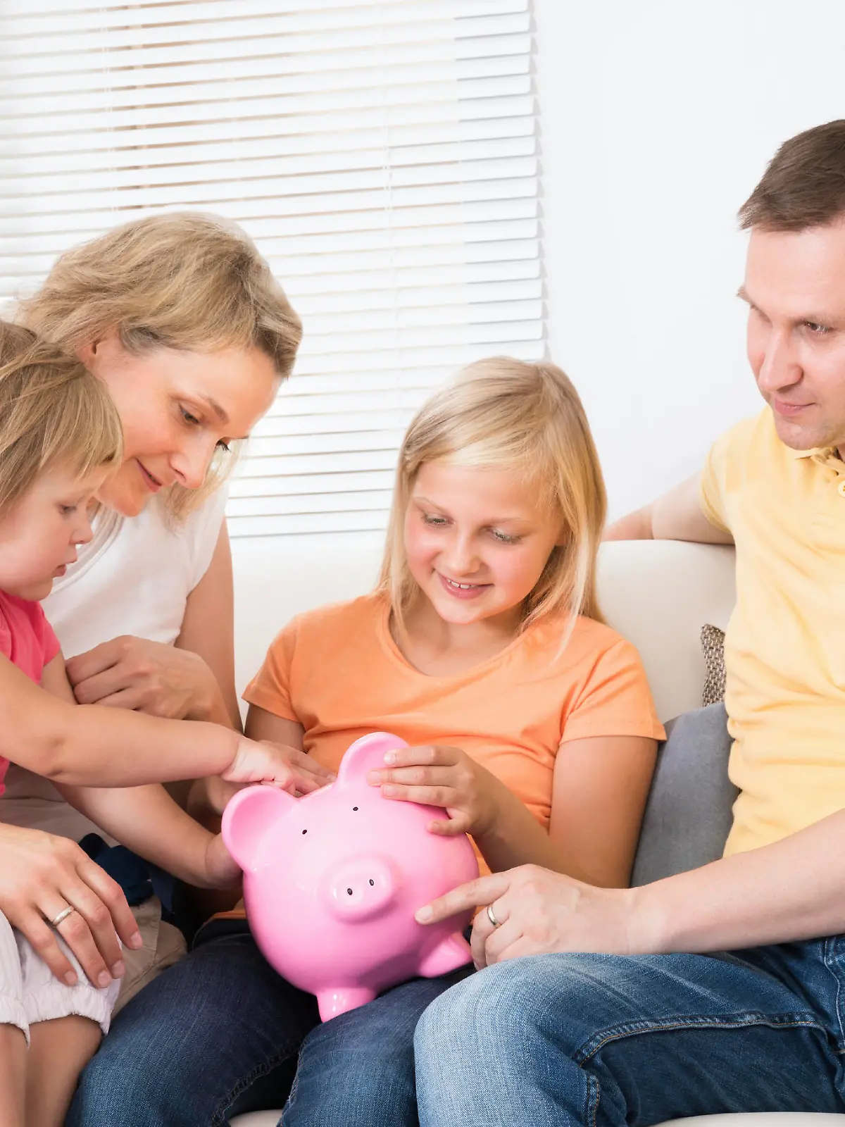 Family Saving Money In Piggybank At Home