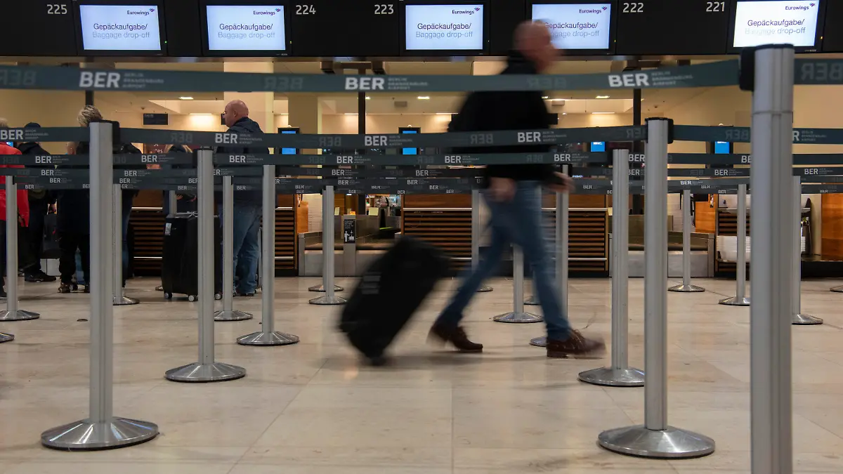 ARCHIV - 18.10.2022, --, Berlin: Ein Reisender geht mit einem Koffer zu einem Check-in-Schalter von Eurowings. Die Gewerkschaft Verdi hat für Mittwoch einen ganztägigen Streik am Hauptstadtflughafen BER angekündigt. (zu dpa «Verdi kündigt ganztägigen Streik am BER an») Foto: Paul Zinken/dpa +++ dpa-Bildfunk +++