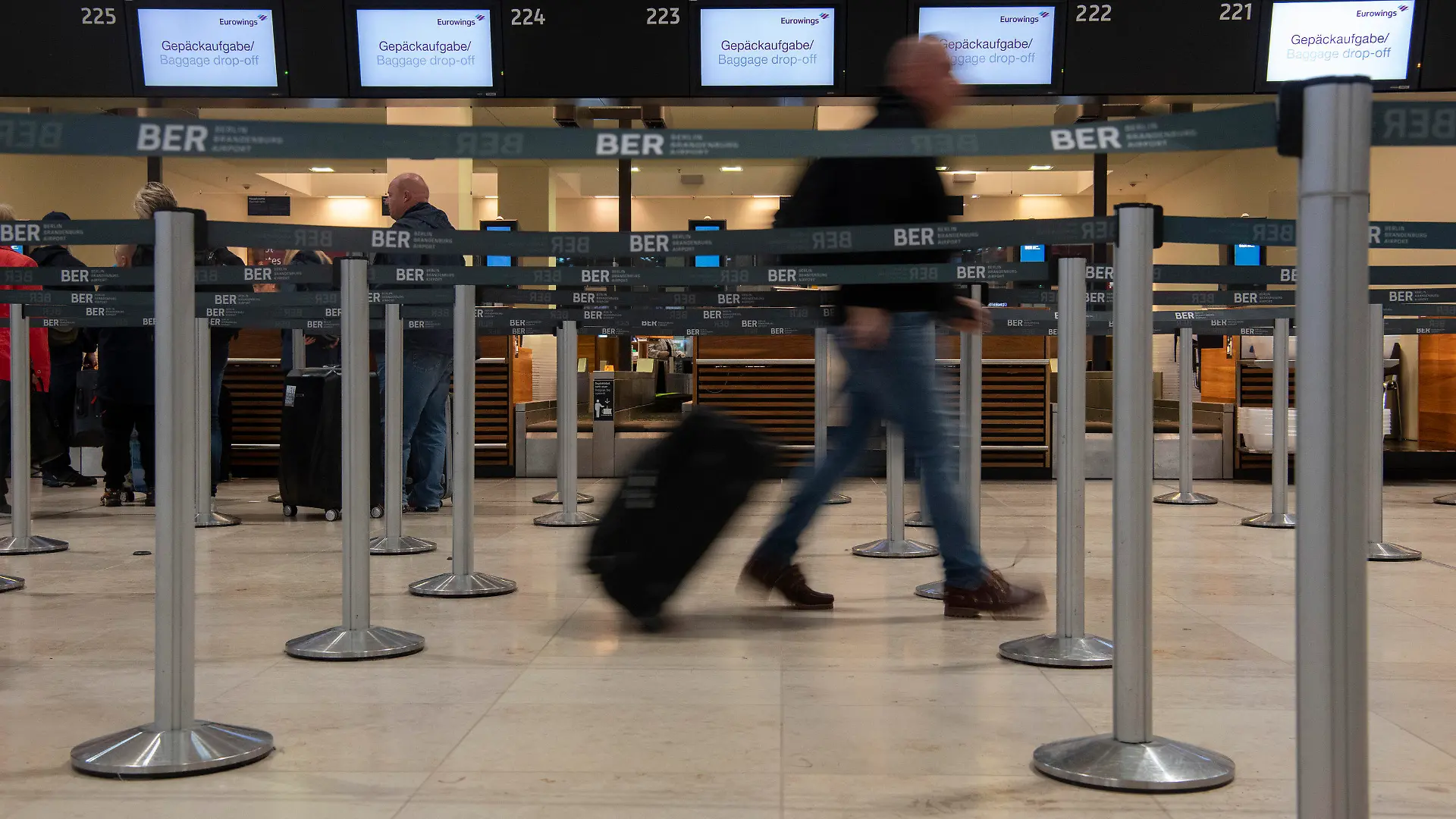 ARCHIV - 18.10.2022, --, Berlin: Ein Reisender geht mit einem Koffer zu einem Check-in-Schalter von Eurowings. Die Gewerkschaft Verdi hat für Mittwoch einen ganztägigen Streik am Hauptstadtflughafen BER angekündigt. (zu dpa «Verdi kündigt ganztägigen Streik am BER an») Foto: Paul Zinken/dpa +++ dpa-Bildfunk +++