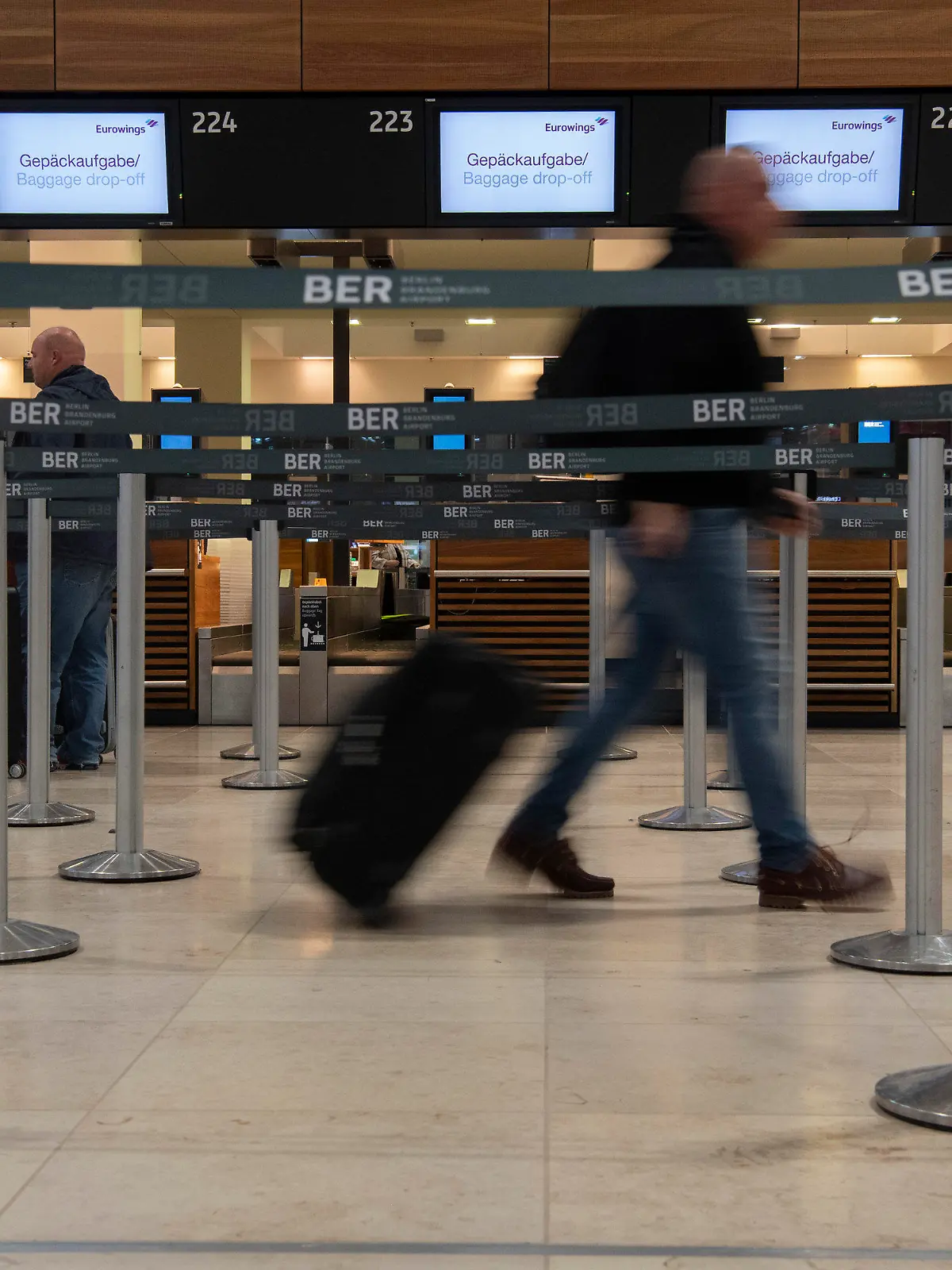ARCHIV - 18.10.2022, --, Berlin: Ein Reisender geht mit einem Koffer zu einem Check-in-Schalter von Eurowings. Die Gewerkschaft Verdi hat für Mittwoch einen ganztägigen Streik am Hauptstadtflughafen BER angekündigt. (zu dpa «Verdi kündigt ganztägigen Streik am BER an») Foto: Paul Zinken/dpa +++ dpa-Bildfunk +++