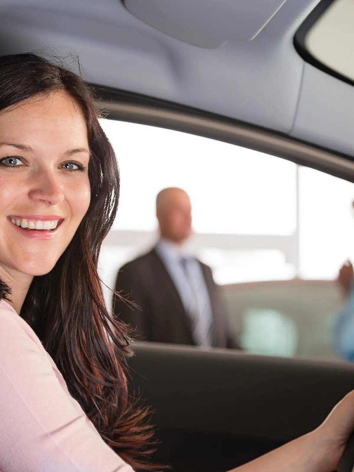 Portrait of smiling woman sitting in car in showroom