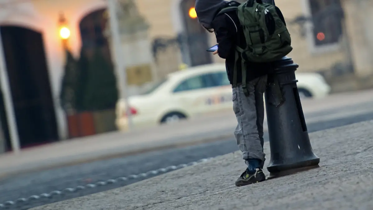 ILLUSTRATION - ARCHIV - Ein Schulkind mit Schulrucksack steht angelehnt an einer Straßenlampe in Dresden und ist mit einem elektronischen Spielgerät beschäftigt, aufgenommen am 04.03.2011. Foto: Arno Burgi/dpa (zu dpa "Eltern dehnen Schulferien oft eigenmächtig aus - Bußgeld droht" vom 29.02.2016) +++(c) dpa - Bildfunk+++