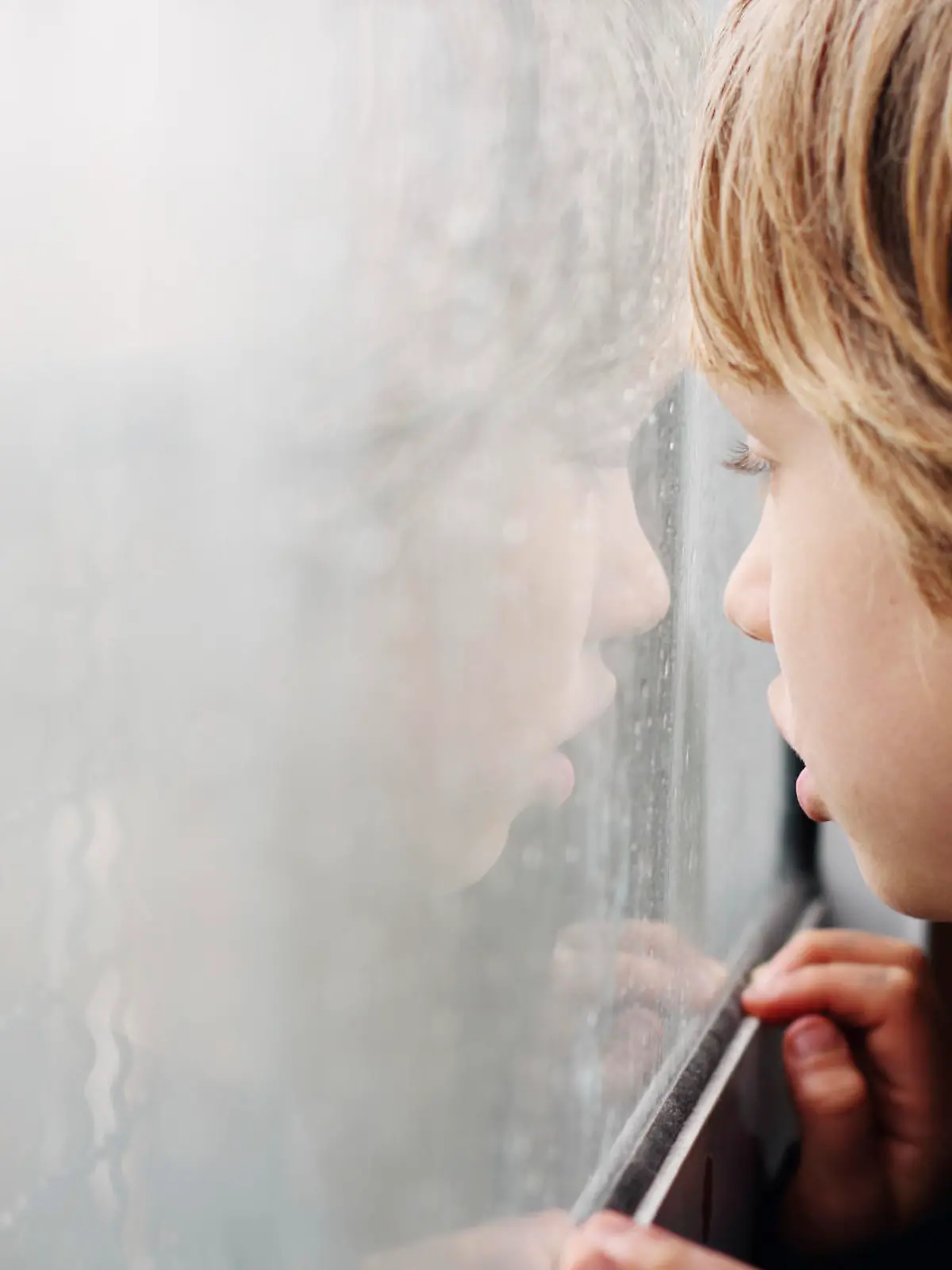 Cute 6 years old boy looking through the window