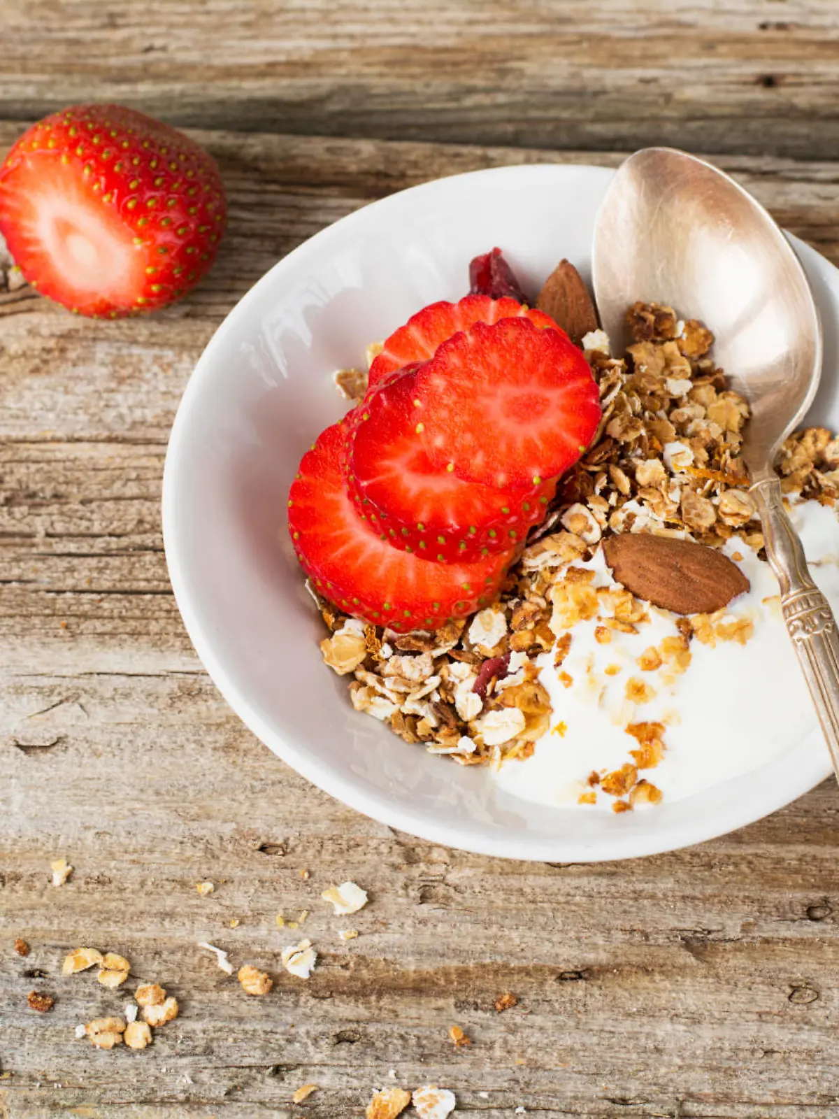 Home crunchy granola with fresh milk and strawberry slices on a simple wooden background. Concept of healthy food simple home. selective Focus
