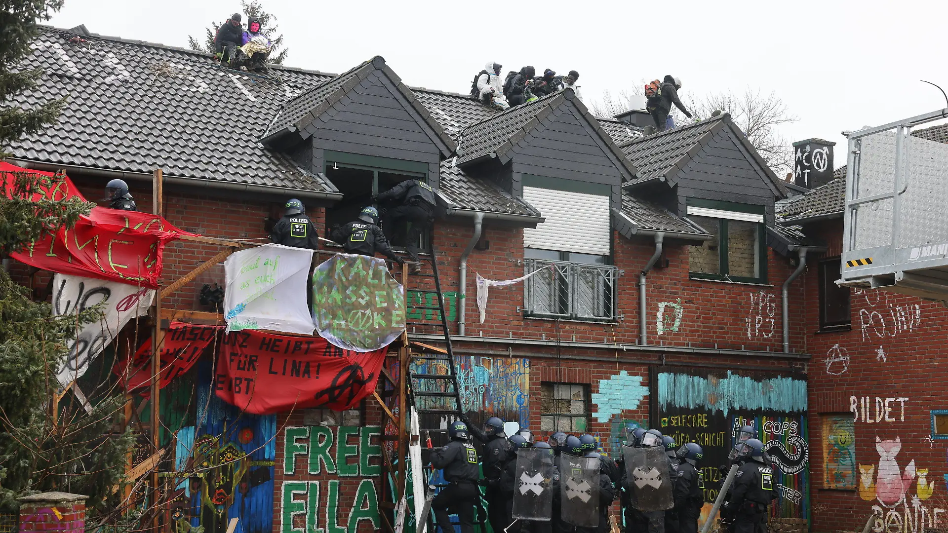 12.01.2023, Nordrhein-Westfalen, Erkelenz: Polizisten verschaffen sich am zweiten Tag der Räumung im von Klimaaktivisten besetzten Braunkohleort Lützerath Zutritt zu einem Gebäude. Der Energiekonzern RWE will die unter Lützerath liegende Kohle abbaggern - dafür soll der Weiler auf dem Gebiet der Stadt Erkelenz am Braunkohletagebau Garzweiler II abgerissen werden. Foto: Oliver Berg/dpa +++ dpa-Bildfunk +++