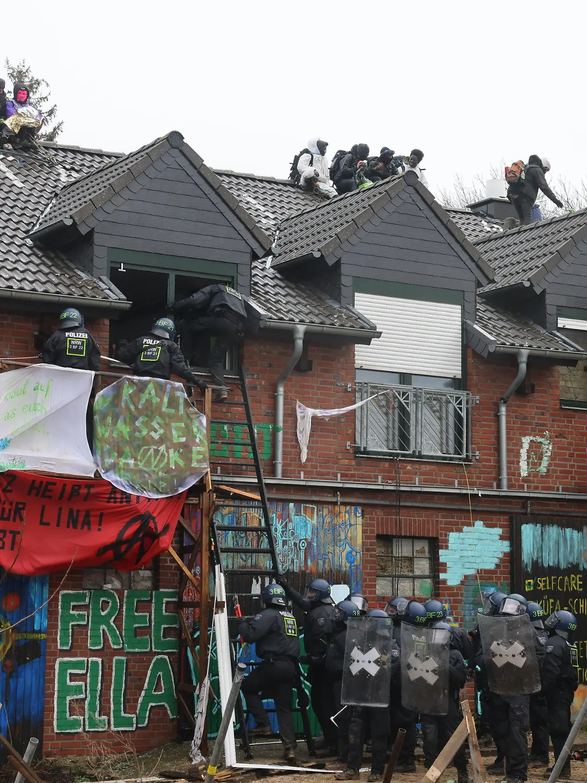 12.01.2023, Nordrhein-Westfalen, Erkelenz: Polizisten verschaffen sich am zweiten Tag der Räumung im von Klimaaktivisten besetzten Braunkohleort Lützerath Zutritt zu einem Gebäude. Der Energiekonzern RWE will die unter Lützerath liegende Kohle abbaggern - dafür soll der Weiler auf dem Gebiet der Stadt Erkelenz am Braunkohletagebau Garzweiler II abgerissen werden. Foto: Oliver Berg/dpa +++ dpa-Bildfunk +++