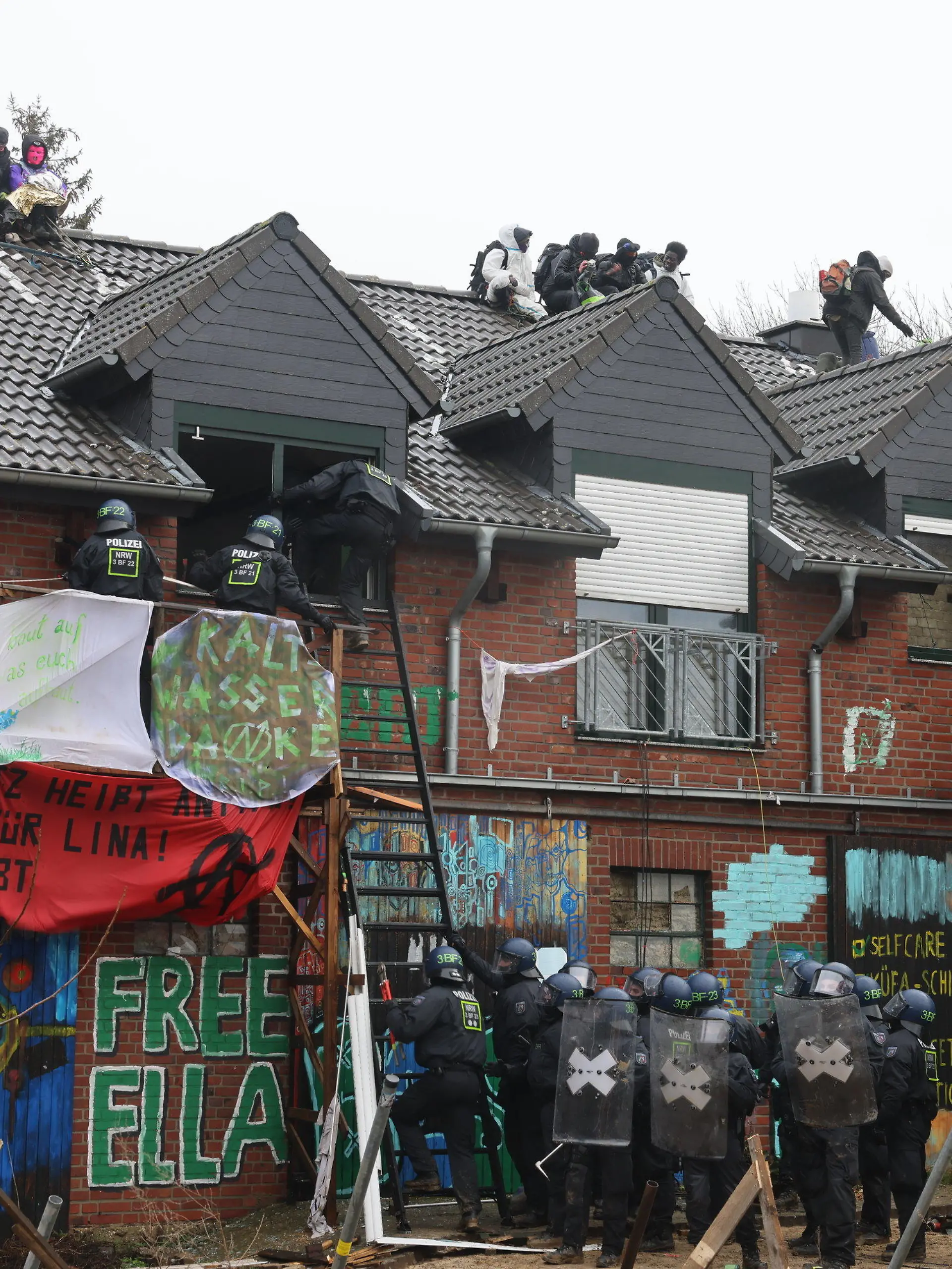 12.01.2023, Nordrhein-Westfalen, Erkelenz: Polizisten verschaffen sich am zweiten Tag der Räumung im von Klimaaktivisten besetzten Braunkohleort Lützerath Zutritt zu einem Gebäude. Der Energiekonzern RWE will die unter Lützerath liegende Kohle abbaggern - dafür soll der Weiler auf dem Gebiet der Stadt Erkelenz am Braunkohletagebau Garzweiler II abgerissen werden. Foto: Oliver Berg/dpa +++ dpa-Bildfunk +++