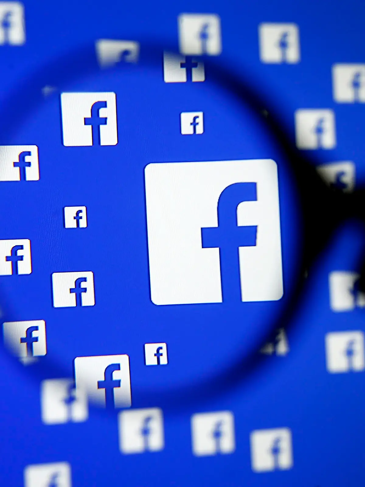 A man poses with a magnifier in front of a Facebook logo on display in this illustration taken in Sarajevo, Bosnia and Herzegovina, in this December 16, 2015 file photo. Facebook Inc is offering employees at its Silicon Valley headquarters up to $15,000 to move closer to the office, a reflection of the workforce challenges many tech companies face in the increasingly expensive and congested San Francisco Bay area.  REUTERS/Dado Ruvic/Files