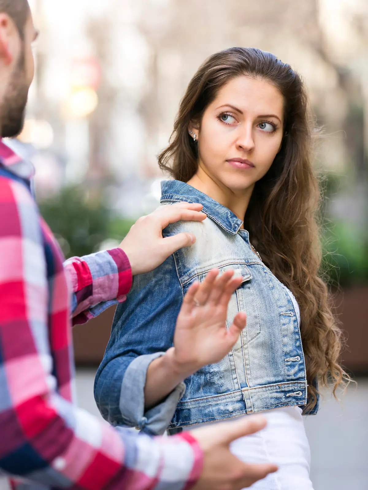 Man is trying to pick up girl on city street outdoors. She is irritated by him and refuses to talk