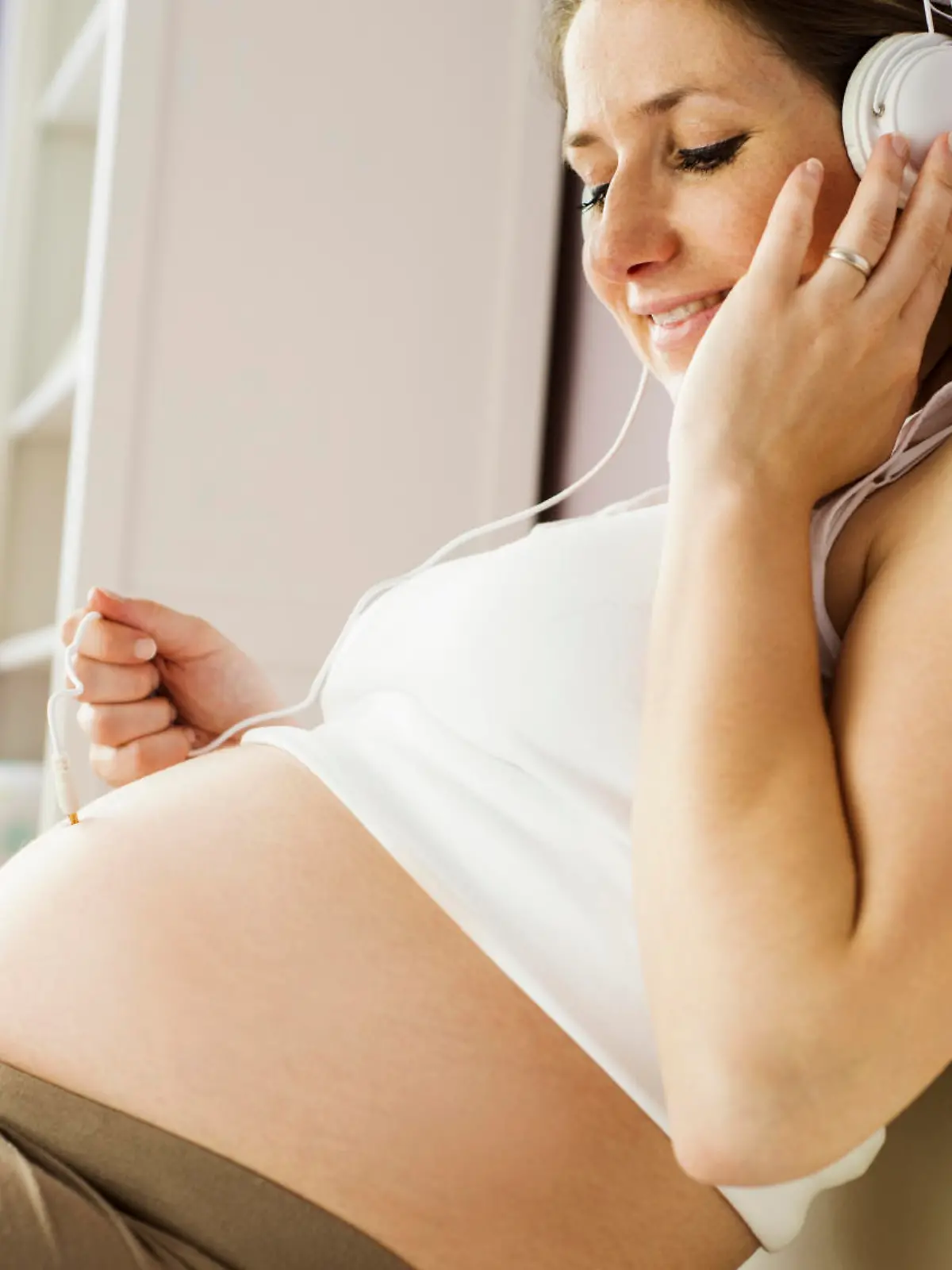 Beautiful pregnant woman listening to her baby with headphones
