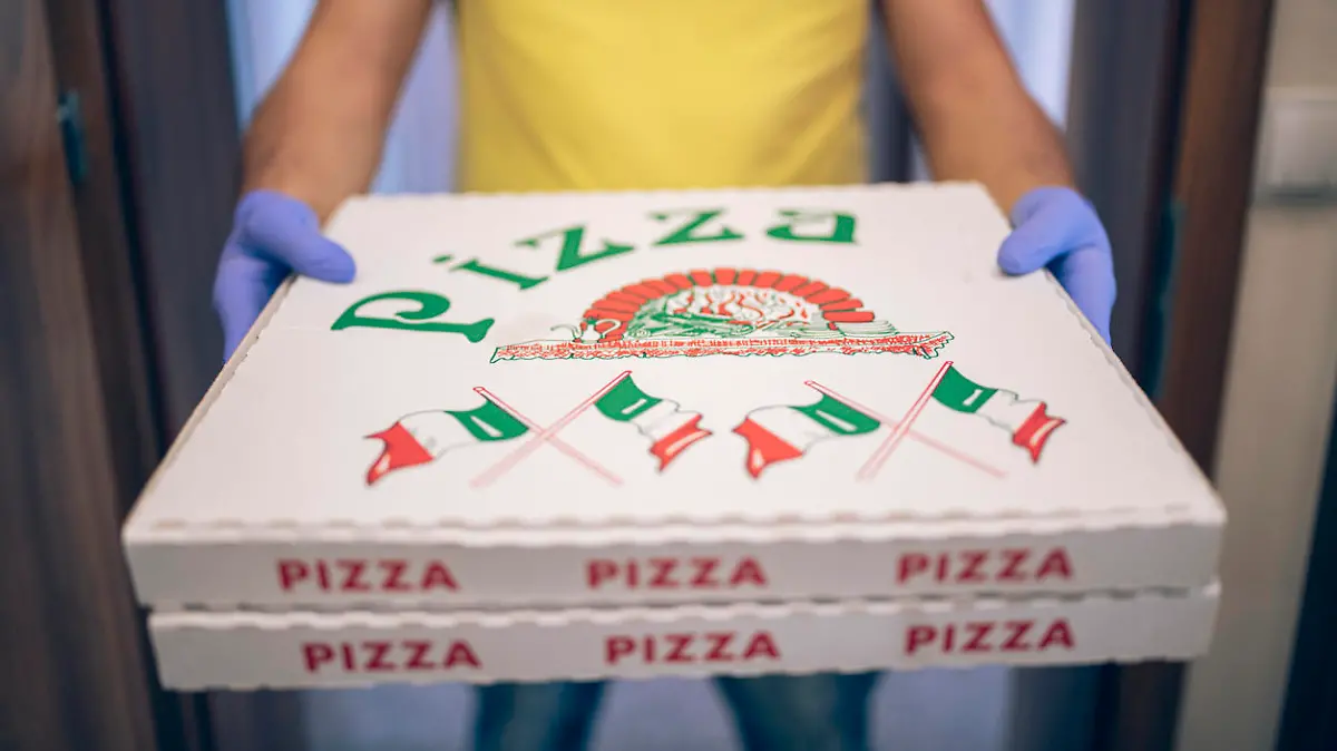 Unrecognizable man with protective gloves holding pizza food, delivery concept in a pandemic.