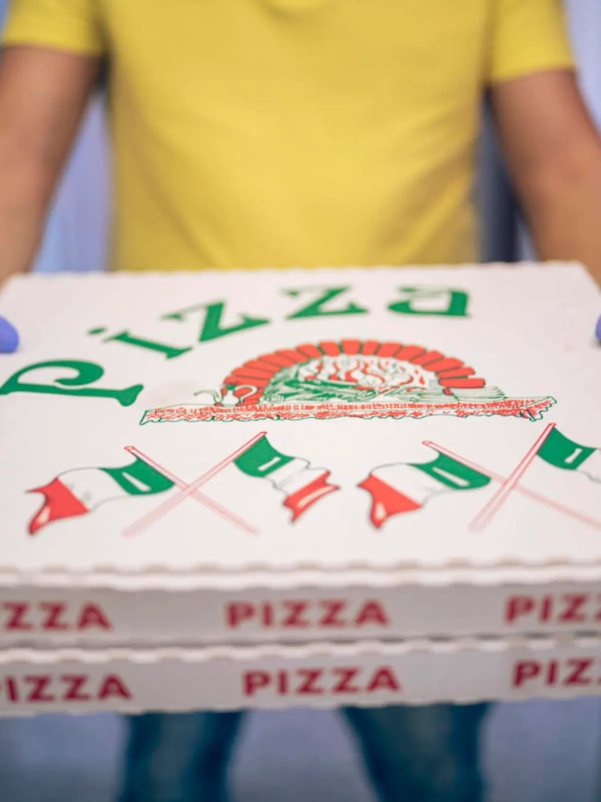 Unrecognizable man with protective gloves holding pizza food, delivery concept in a pandemic.