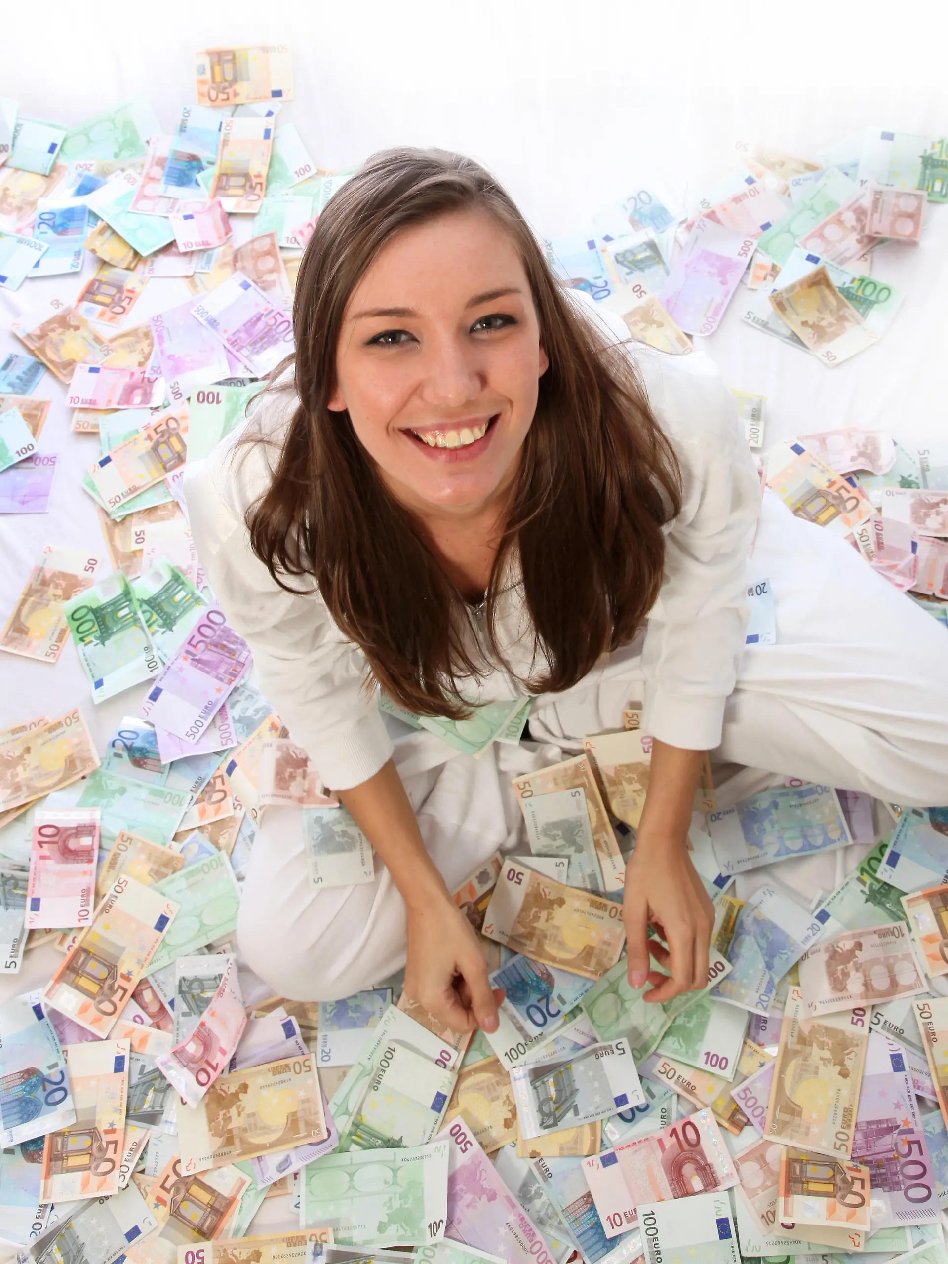 Junge Frau sitzt glücklich im Geld Sie sitzt auf vielen Euro scheinen
