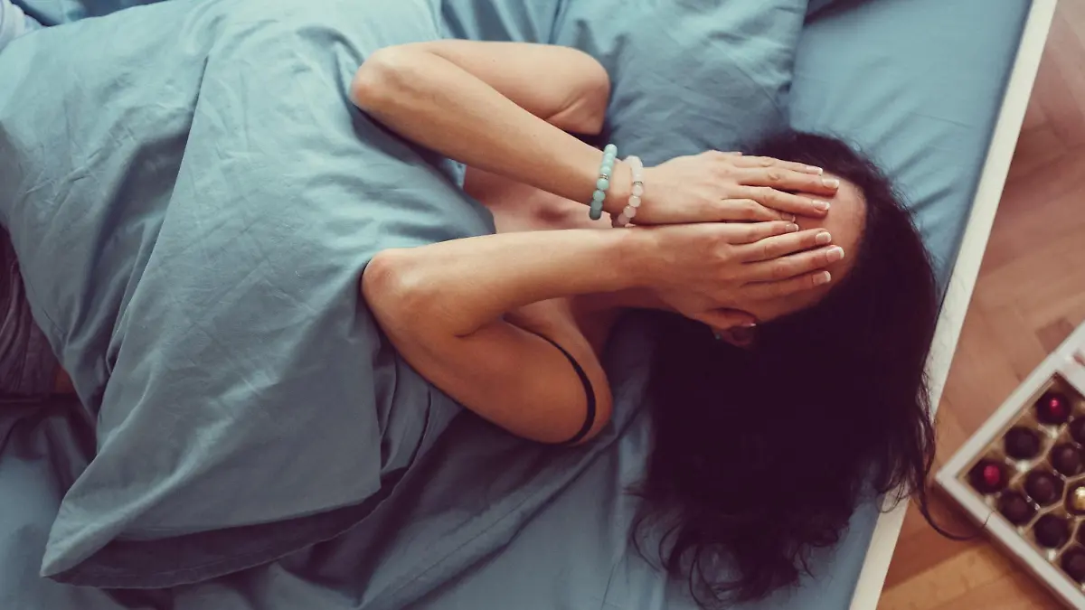 Depressed woman in bed with hands on face