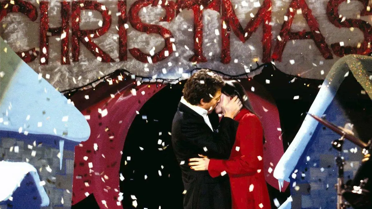 Der britische Premierminister (Hugh Grant) küsst im neuen Kinofilm 'Tatsächlich ... Liebe' (Szenenfoto) unter einem Schild mit der Aufschrift 'Merry Christmas' (Frohe Weihnachten) die hübsche Natalie (Martine McCutcheon). Zwei Monate vor Heiligabend sehnt sich ganz London nach der Liebe. Selbst der Premierminister wird vom Gefühlstaumel nicht verschont und verliebt sich in sein Serviermädchen. Neben diesen lieben und leiden unter anderem der Schriftsteller Jamie, ein portugiesisches Hausmädchen, der Verlagsleiter Harry und der abgetakelte Sänger Billy. Sie alle durchlaufen eine Reihe von Verstrickungen und Irrtümern, bis der Gefühlsrausch an Heiligabend schließlich in diversen Liebesgeständnissen gipfelt... Starttermin der Komödie: 20.11.2003.