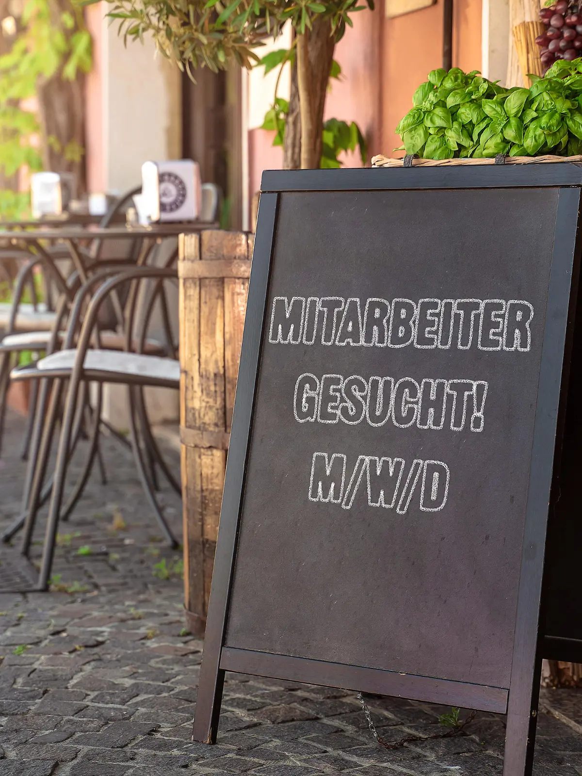 Jobsuche, Aufsteller vor einem Restaurant oder Cafe mit der Aufschrift Mitarbeiter gesucht. Werbung für Arbeitsplatz, anwerben von Aushilfen und Arbeitern in der Gastronomie FOTOMONTAGE