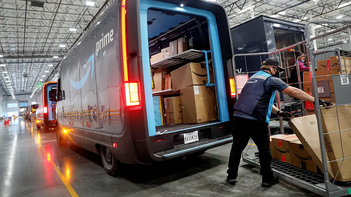 Workers load packages into Amazon Rivian Electric trucks at an Amazon facility in Poway, California, U.S., November 16, 2022. REUTERS/Sandy Huffaker