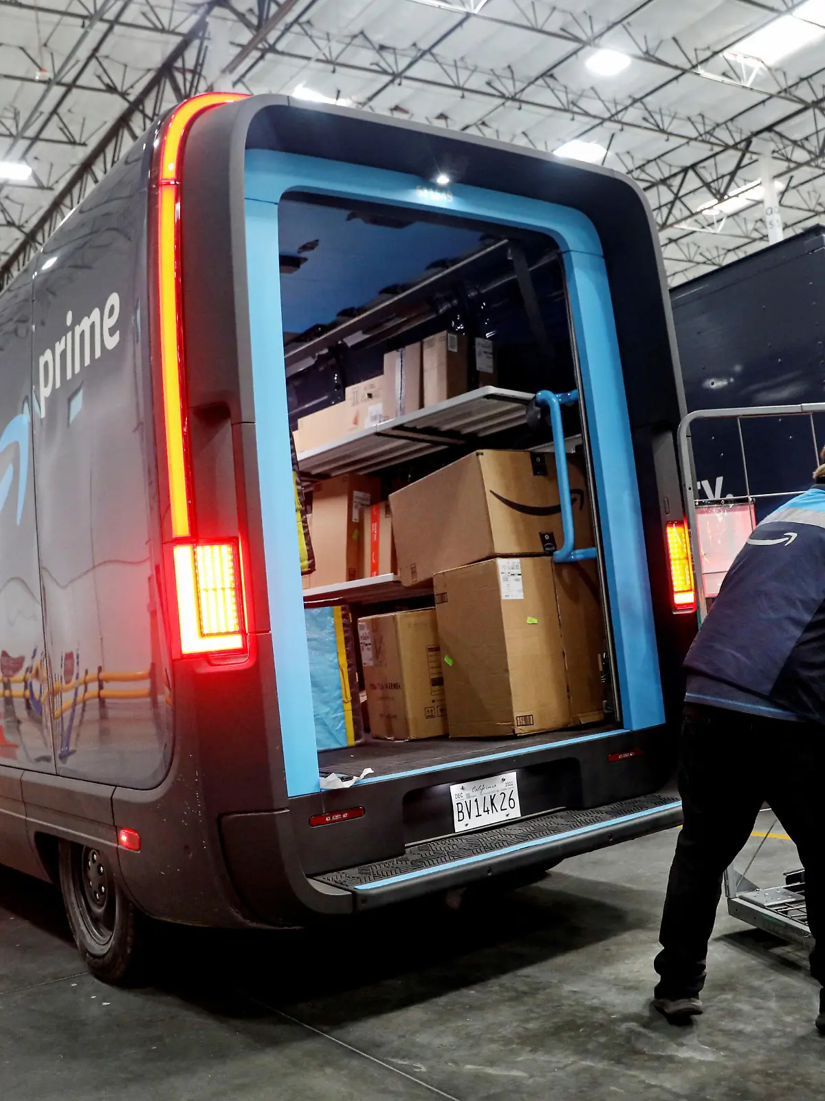 Workers load packages into Amazon Rivian Electric trucks at an Amazon facility in Poway, California, U.S., November 16, 2022. REUTERS/Sandy Huffaker