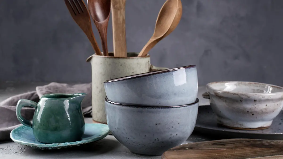 Collection of natural rustic handmade crockery tableware in neutral tones on grey background