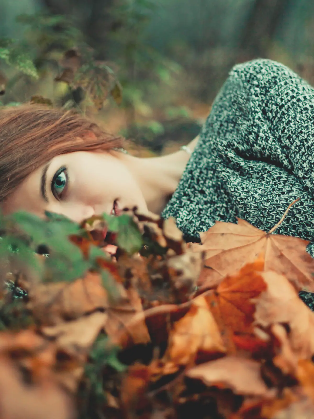 Portrait of beautiful girl with blue eyes. Lay on the ground in the forest