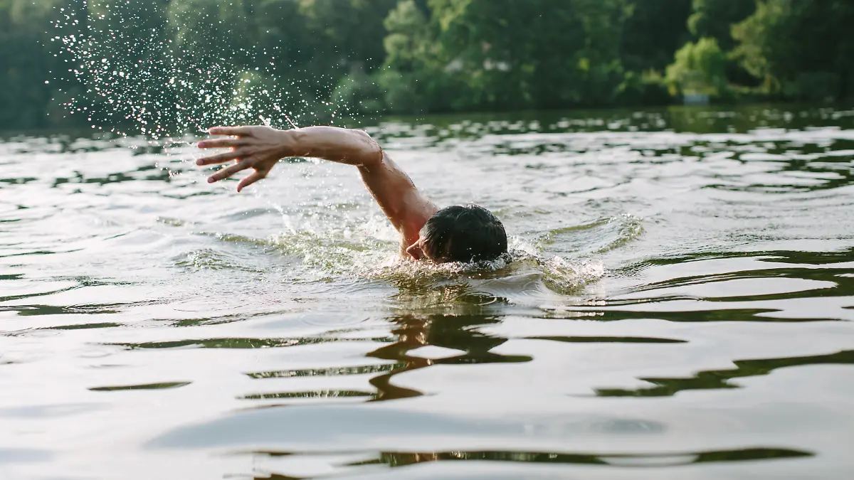 Young man swimming in a lake in Berlin's surroundings